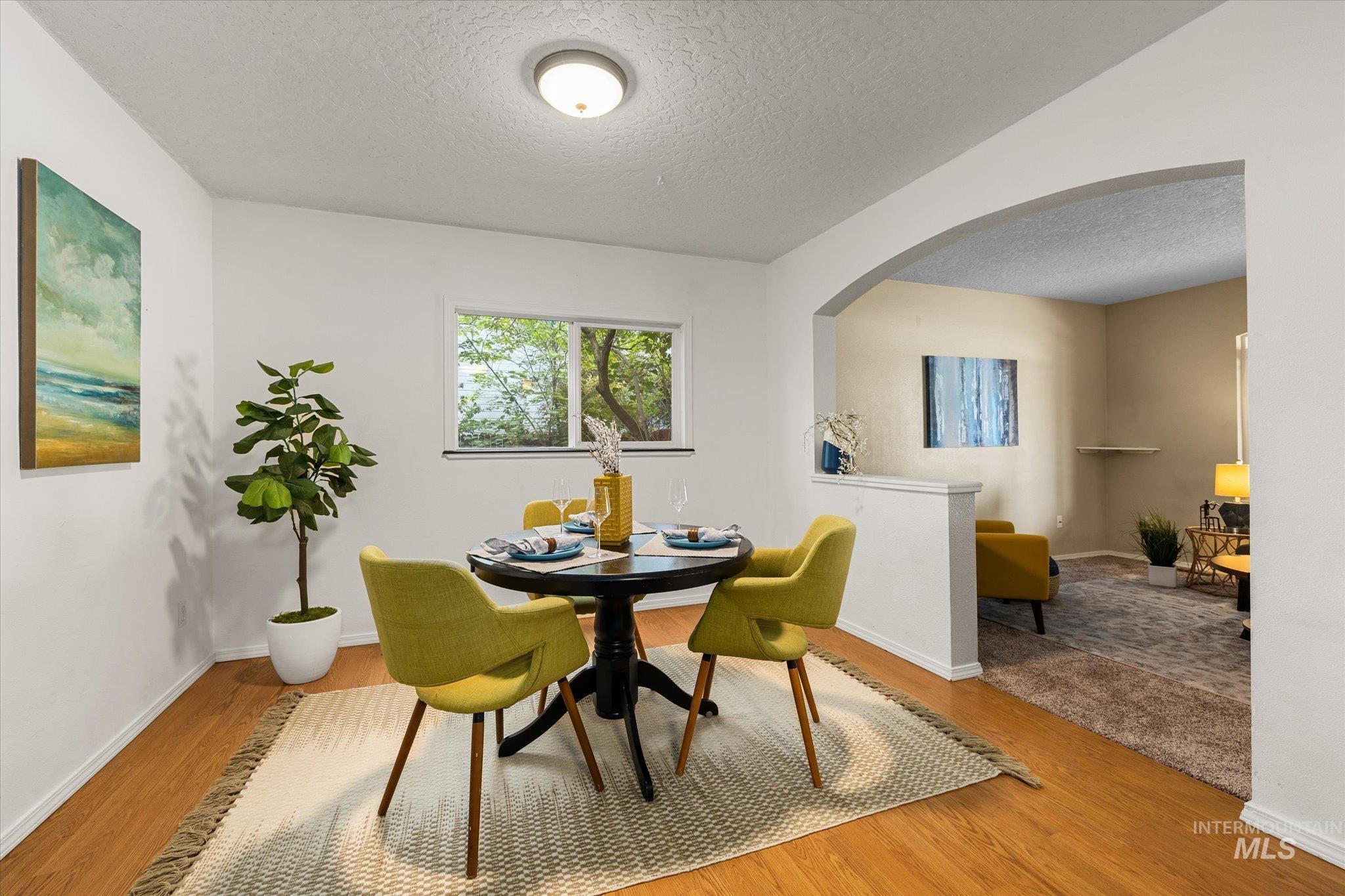 Dining area with arched walkways, a textured ceiling, and wood finished floors