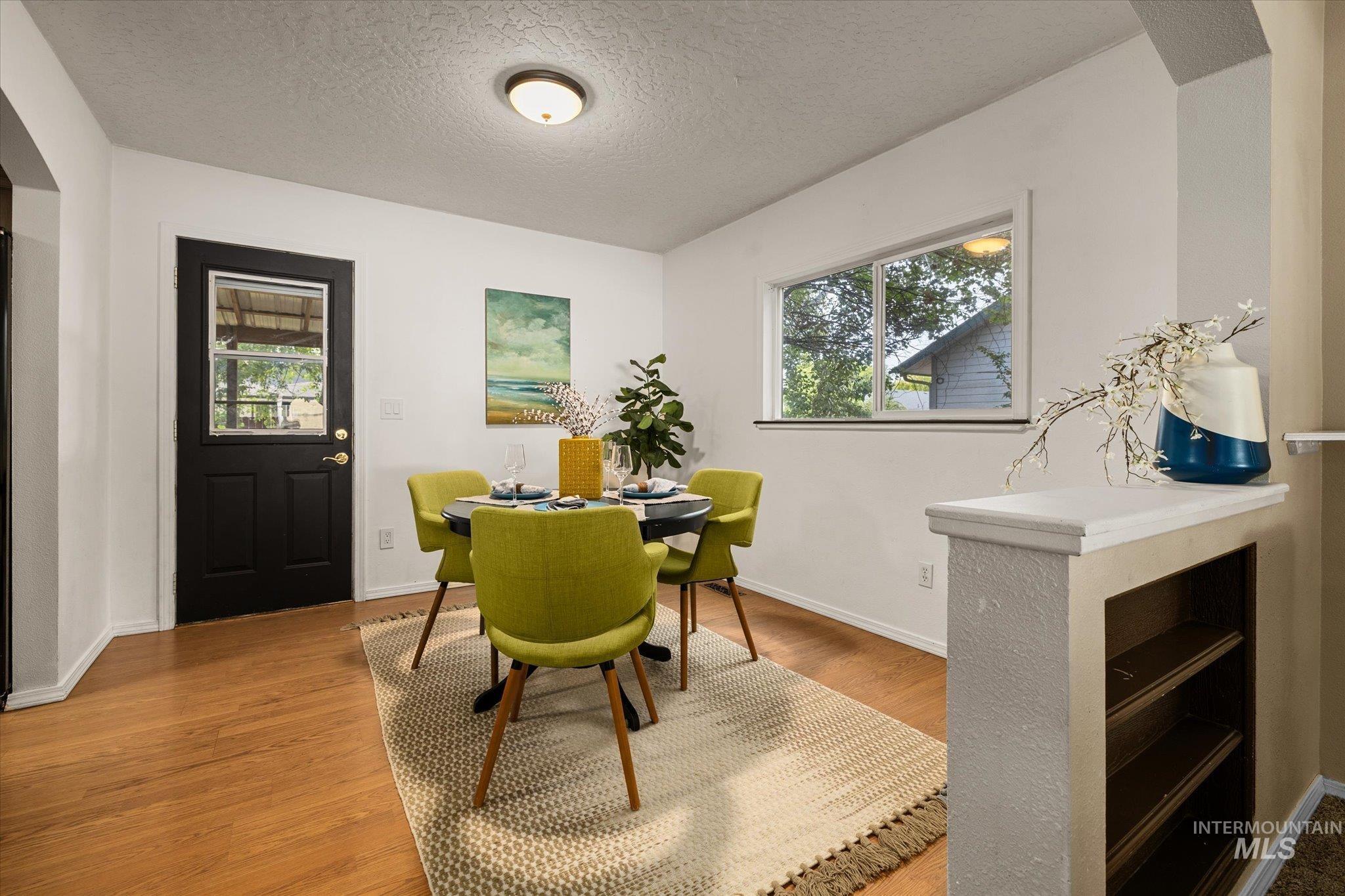 Dining room featuring a textured ceiling, light wood finished floors, plenty of natural light, and arched walkways