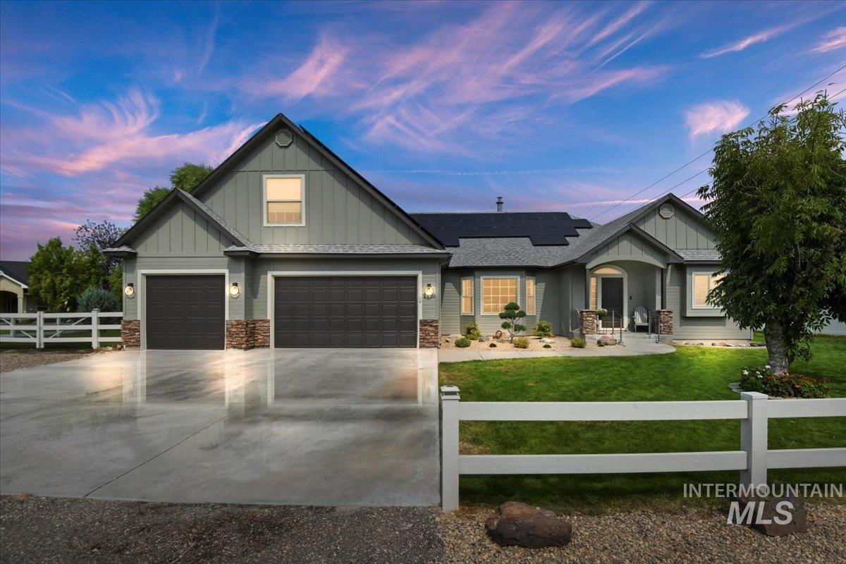 Craftsman house featuring a fenced front yard, board and batten siding, solar panels, and concrete driveway