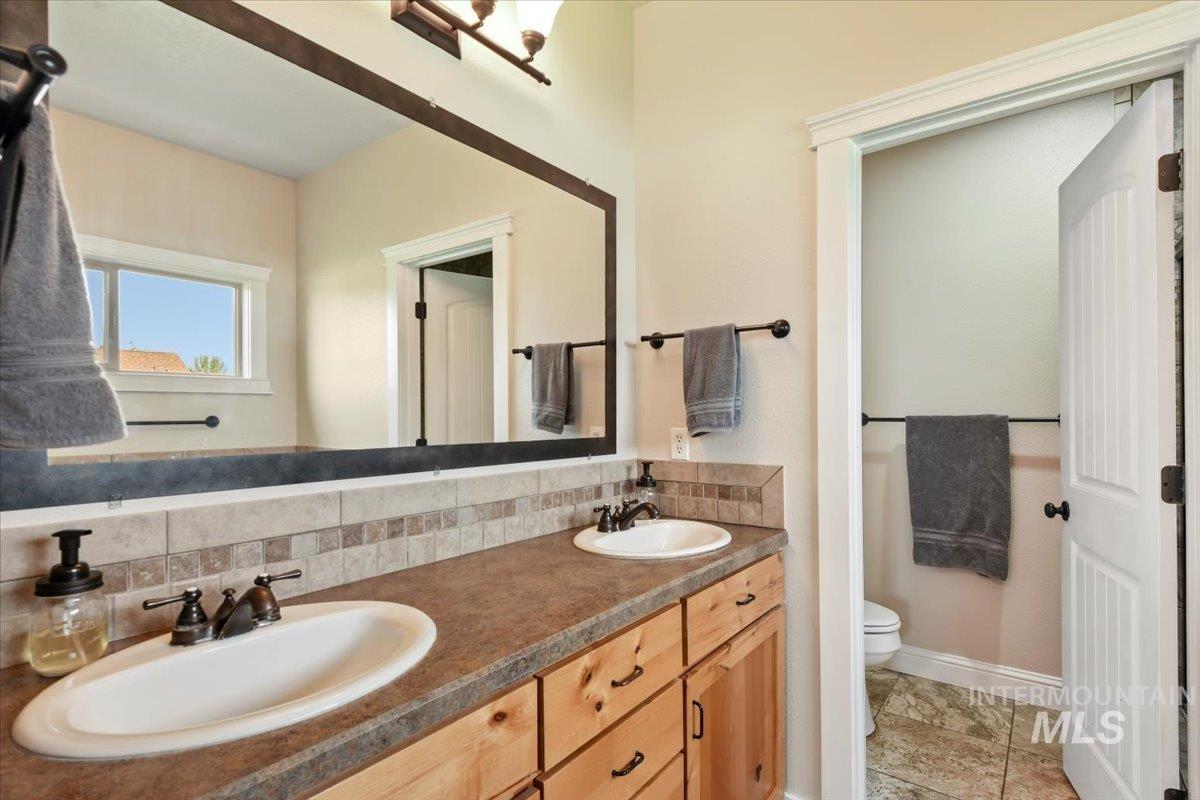 Bathroom featuring double vanity and decorative backsplash