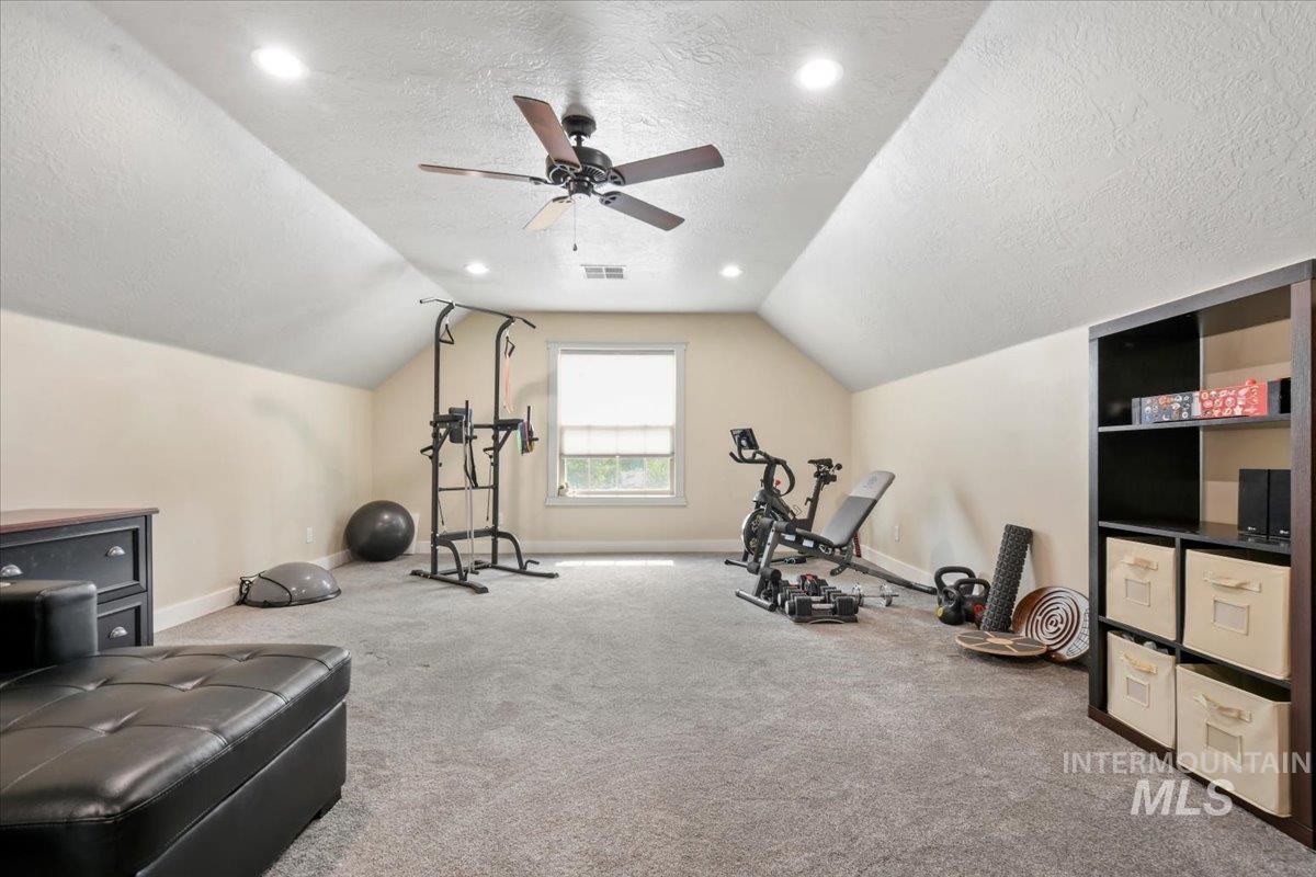 Workout area with a textured ceiling, vaulted ceiling, carpet, ceiling fan, and recessed lighting