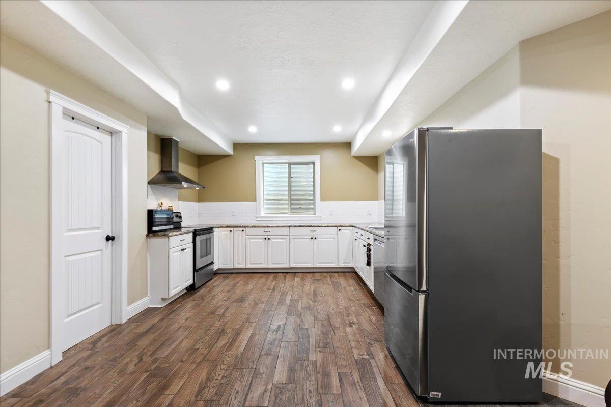 Kitchen with white cabinetry, stainless steel appliances, dark wood-style floors, tasteful backsplash, and recessed lighting