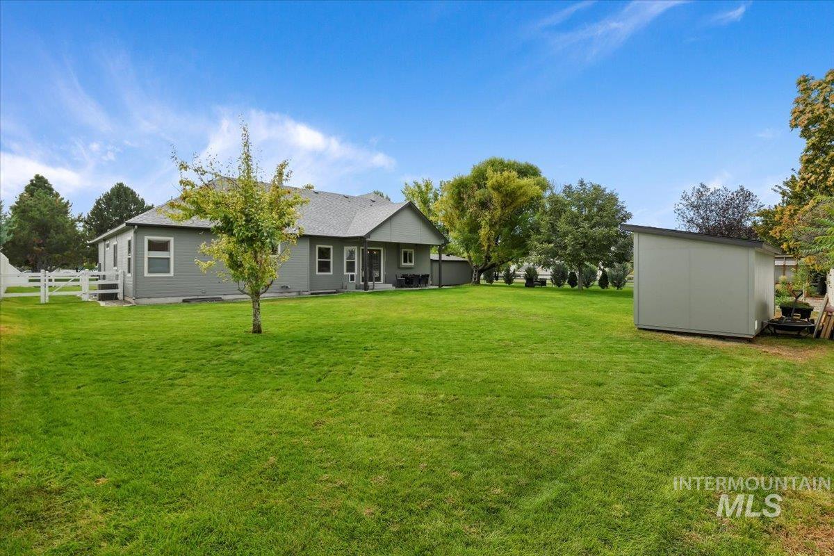 View of grassy yard featuring a patio and a storage unit
