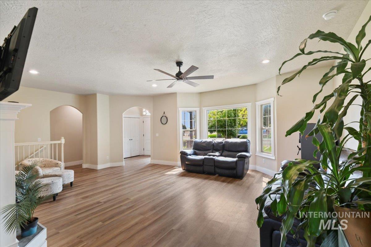 Living area featuring light wood-style flooring, recessed lighting, arched walkways, a textured ceiling, and ceiling fan