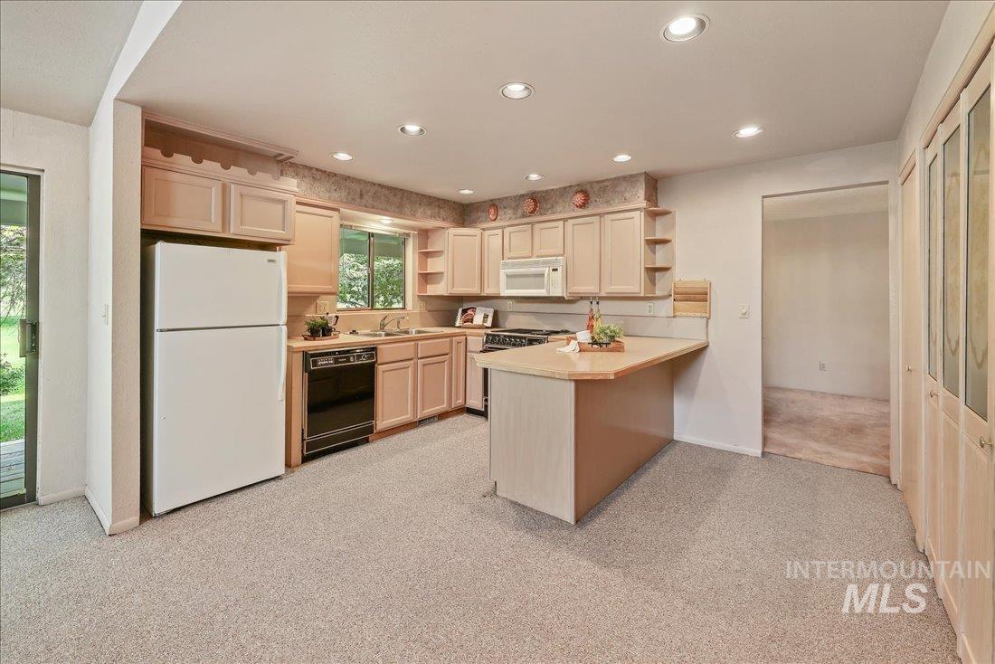 Kitchen with open shelves, light countertops, white appliances, light colored carpet, and a peninsula