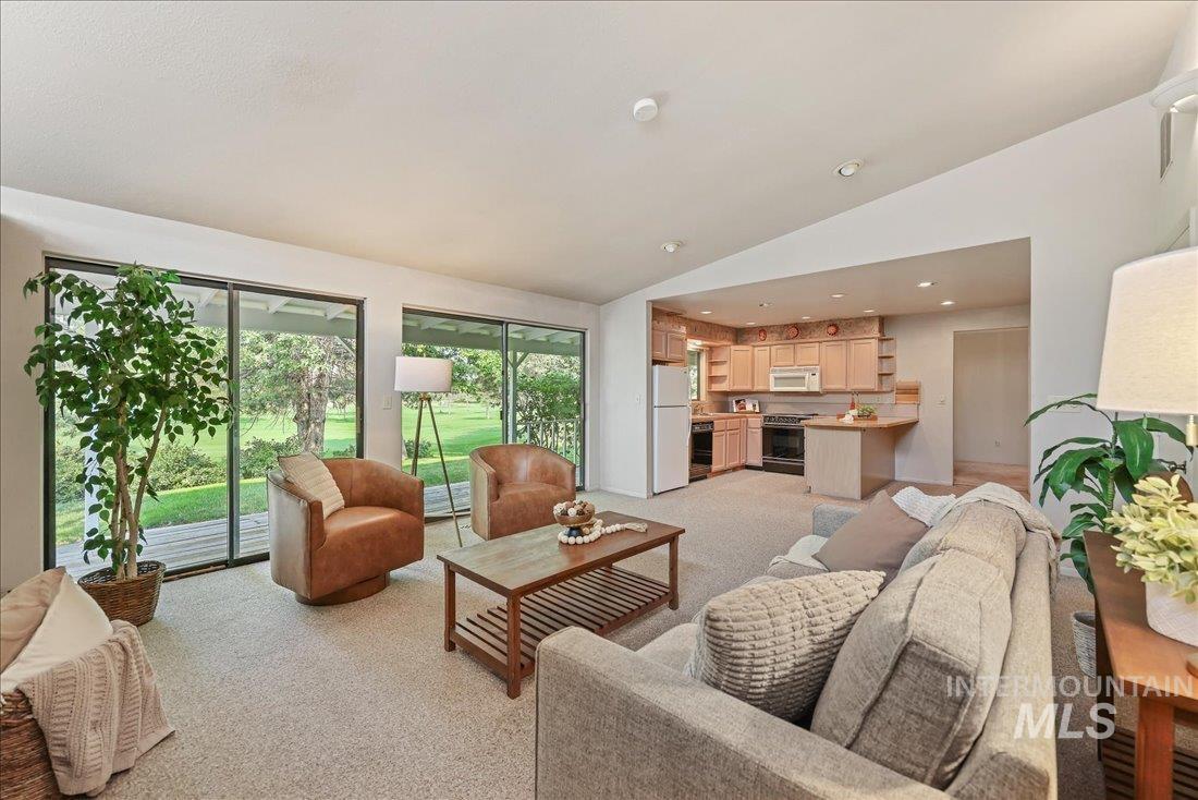 Living area featuring light colored carpet, lofted ceiling, and recessed lighting