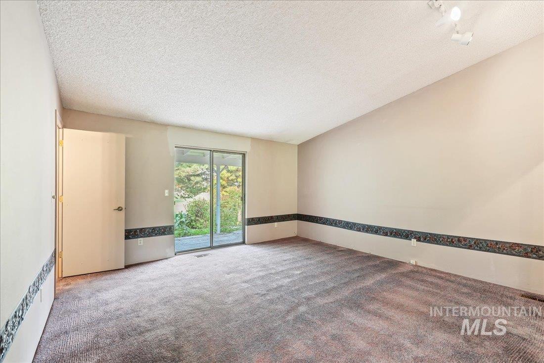 Carpeted spare room with a textured ceiling and vaulted ceiling