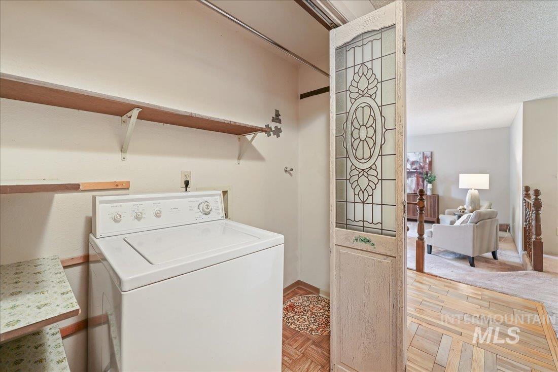 Washroom featuring washer / clothes dryer, a textured ceiling, and parquet floors