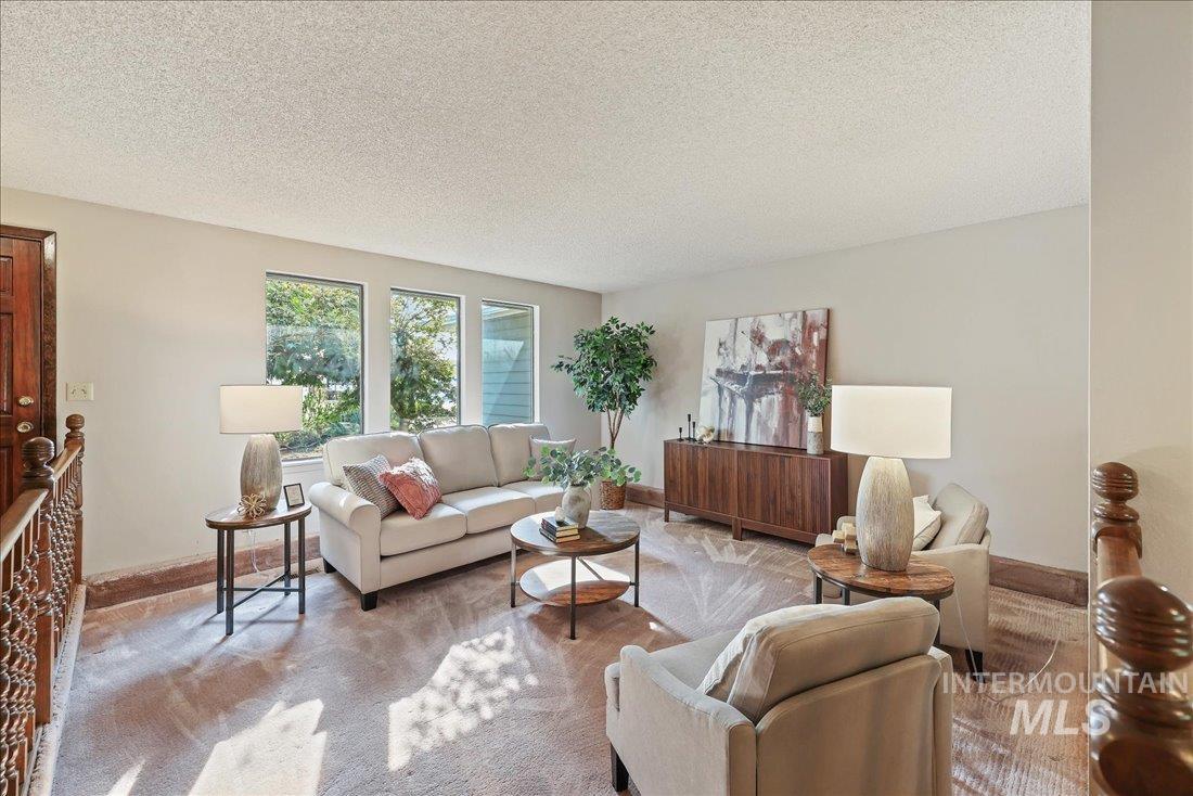 Carpeted living room featuring a textured ceiling and baseboards