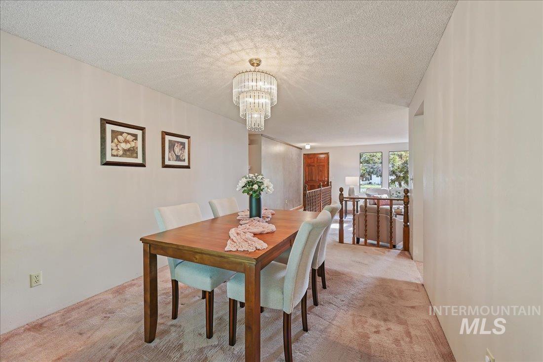 Dining space with light colored carpet, a textured ceiling, and a chandelier