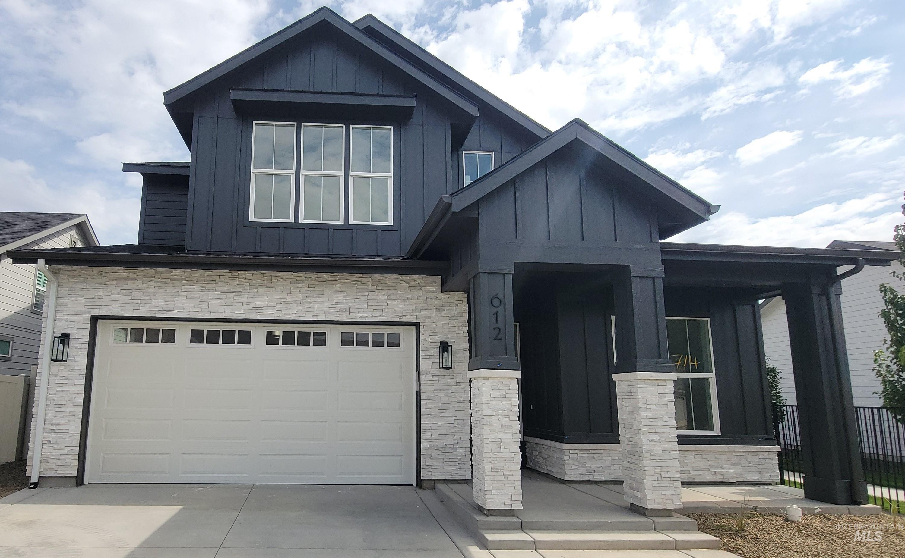 Craftsman inspired home with stone siding, covered porch, board and batten siding, and a garage