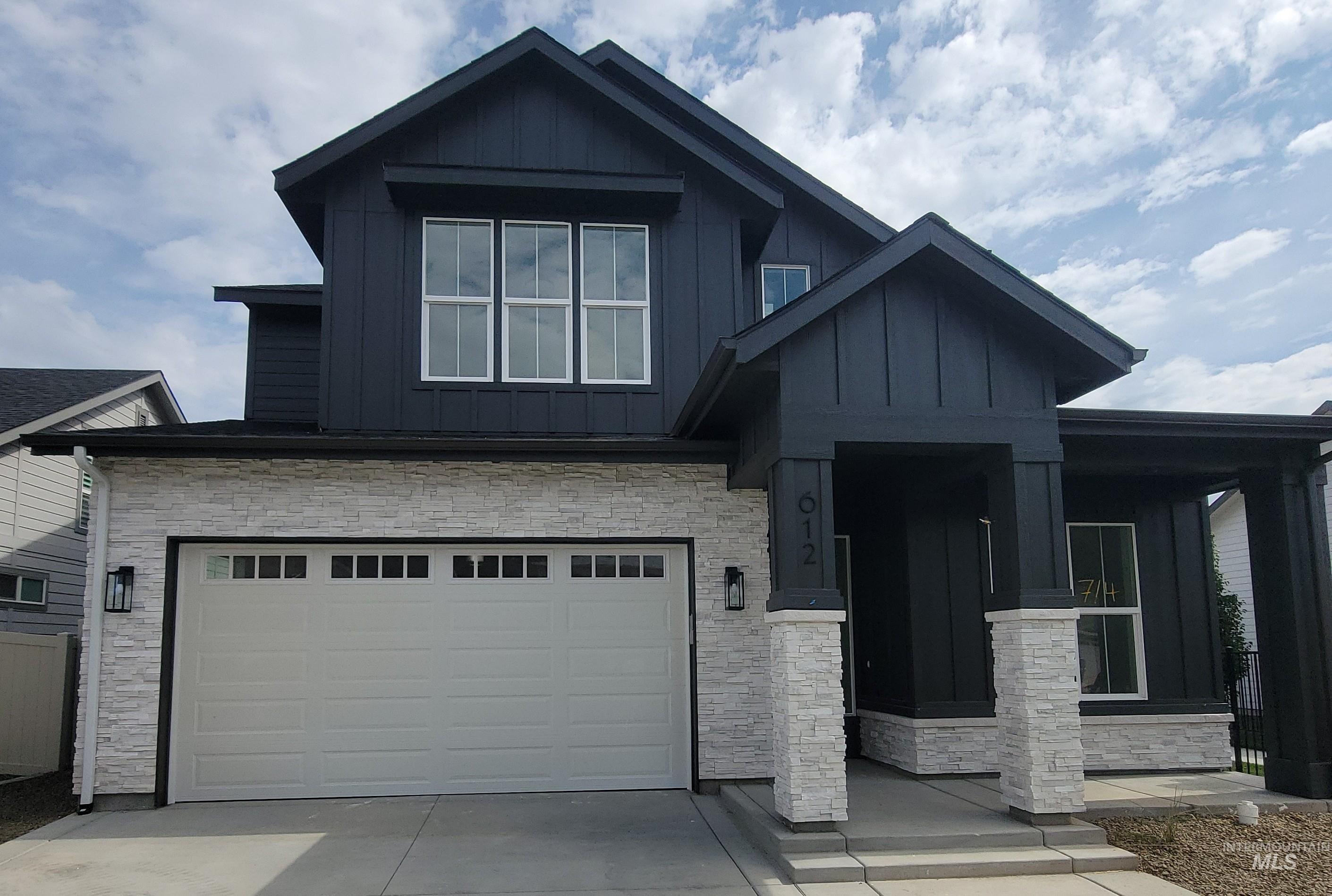 Craftsman-style home with stone siding, a porch, board and batten siding, concrete driveway, and an attached garage