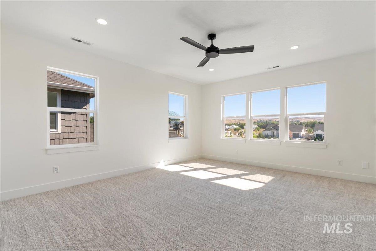 Carpeted spare room featuring healthy amount of natural light, recessed lighting, and ceiling fan