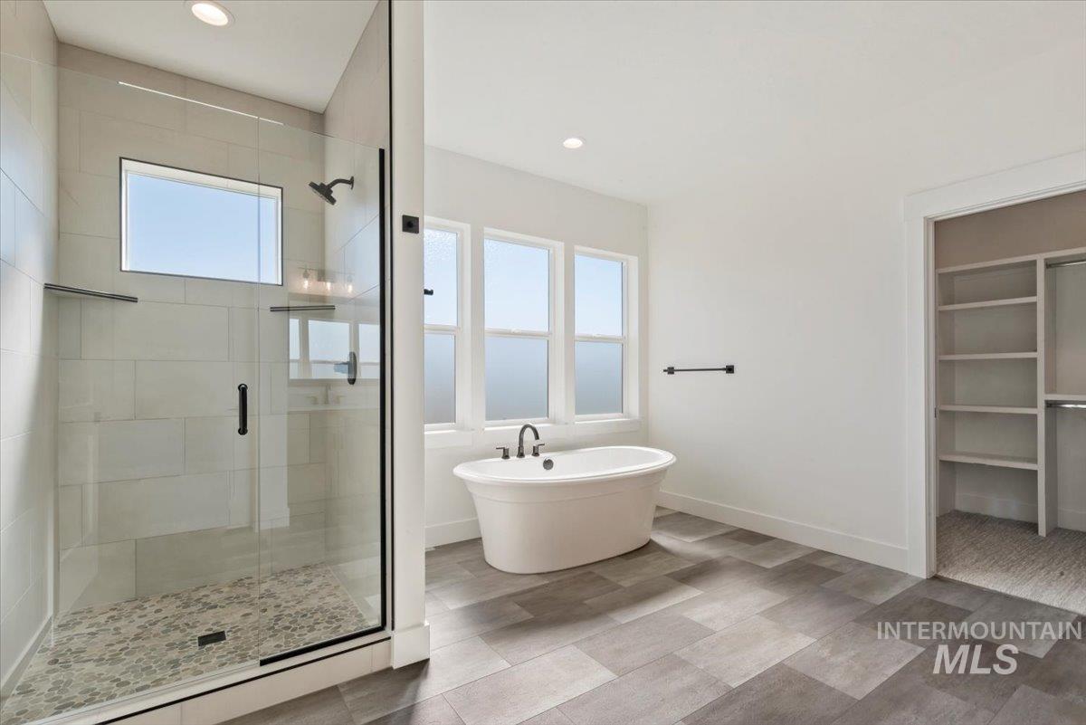 Full bath with a stall shower, a freestanding tub, plenty of natural light, a walk in closet, and recessed lighting