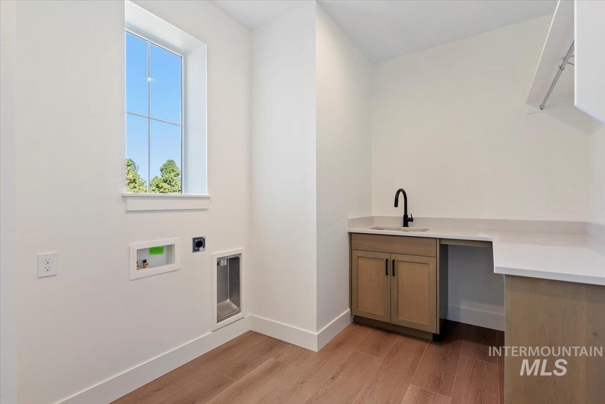 Laundry area featuring light wood-style flooring, washer hookup, electric dryer hookup, and cabinet space