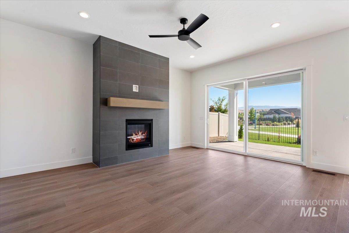 Unfurnished living room featuring wood finished floors, a fireplace, a ceiling fan, and recessed lighting