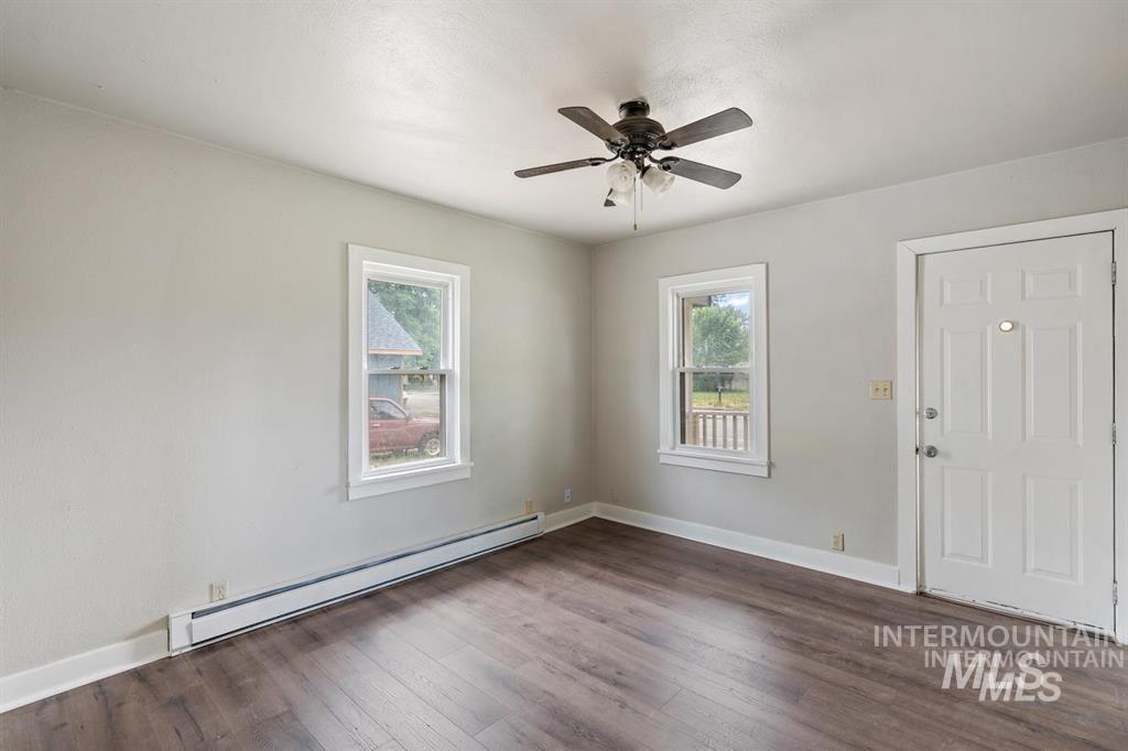 Foyer entrance with baseboard heating, dark wood-type flooring, and a ceiling fan