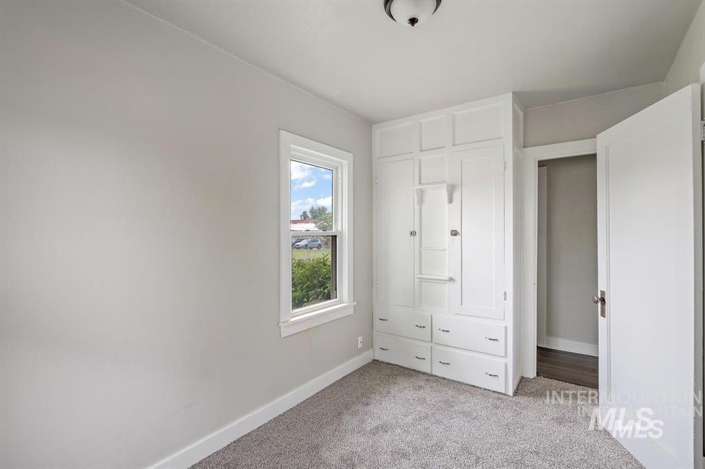 Unfurnished bedroom with light colored carpet and baseboards