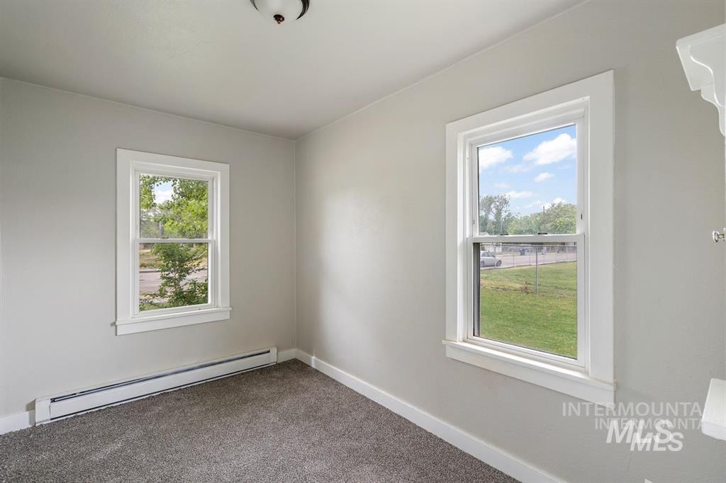 Carpeted empty room with baseboard heating and baseboards