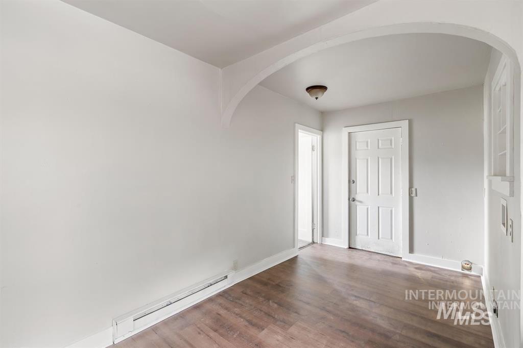 Foyer with baseboard heating, dark wood-type flooring, and arched walkways