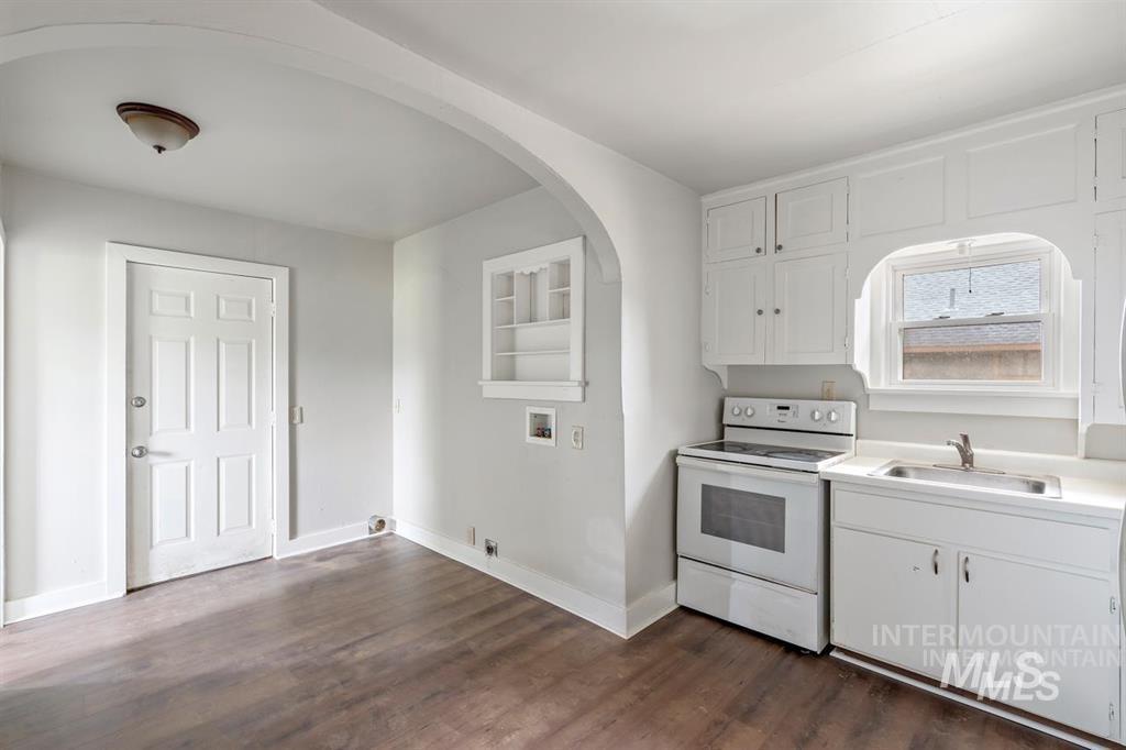 Kitchen with white range with electric cooktop, white cabinetry, light countertops, and dark wood-type flooring