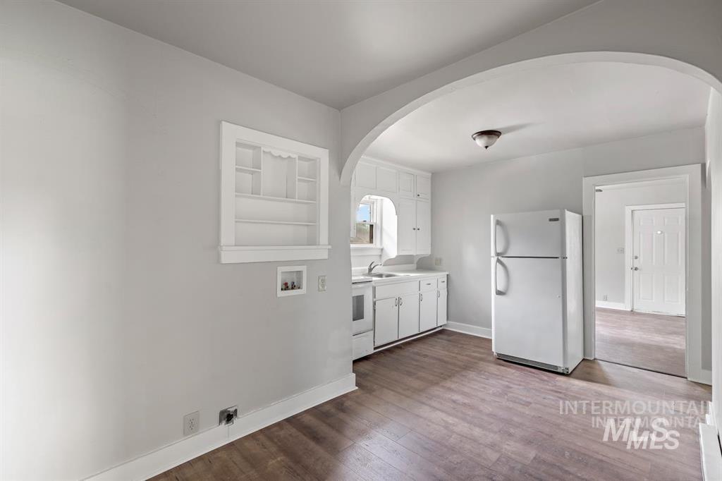 Laundry area with arched walkways, dark wood finished floors, washer hookup, and hookup for an electric dryer