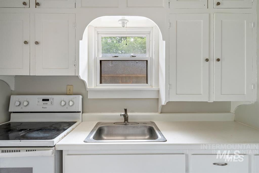 Kitchen with white range with electric cooktop, white cabinets, and light countertops