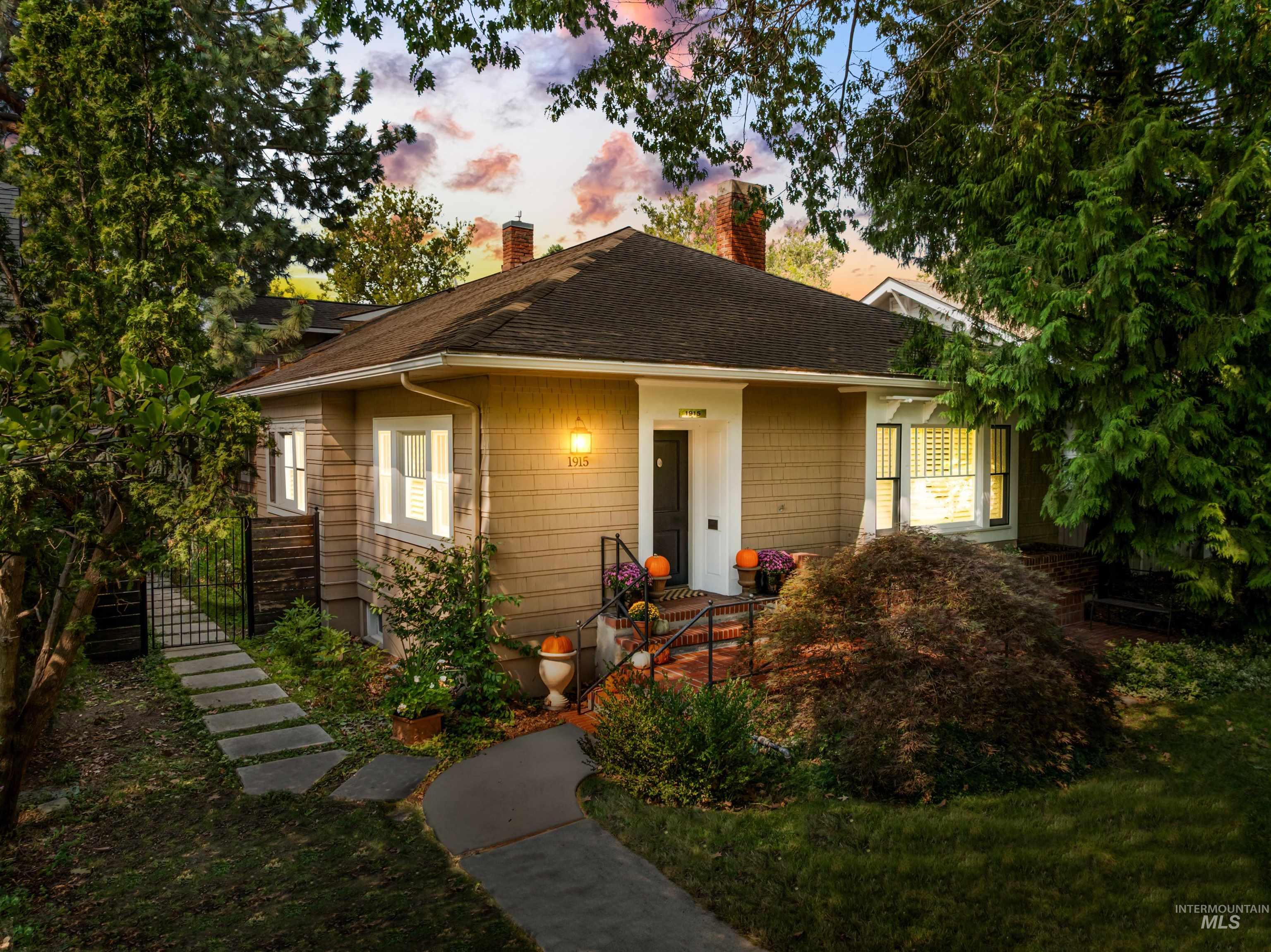 Bungalow-style house featuring roof with shingles, a chimney, and a gate