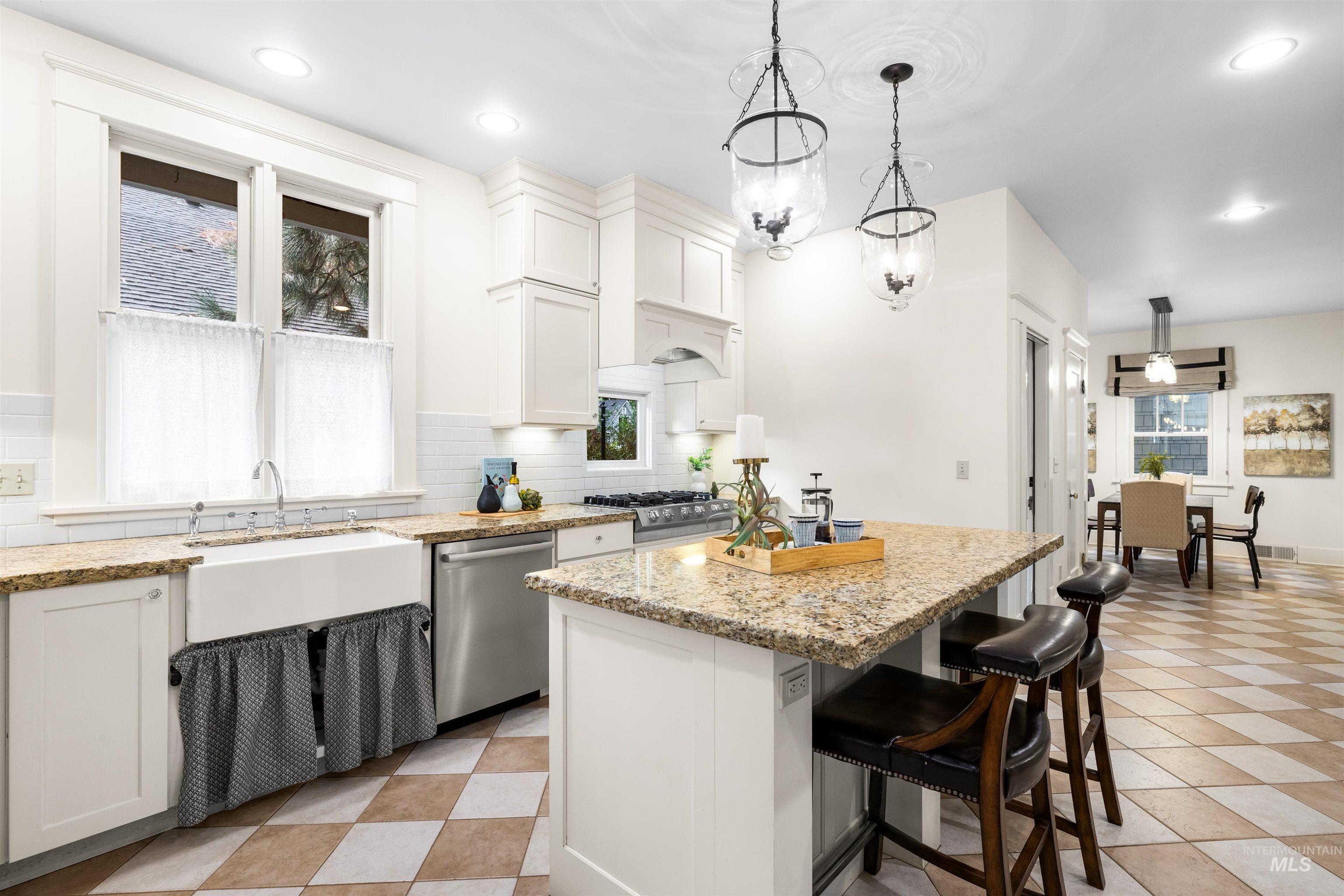 Kitchen featuring white cabinets, tasteful backsplash, a kitchen breakfast bar, a kitchen island, and stainless steel dishwasher
