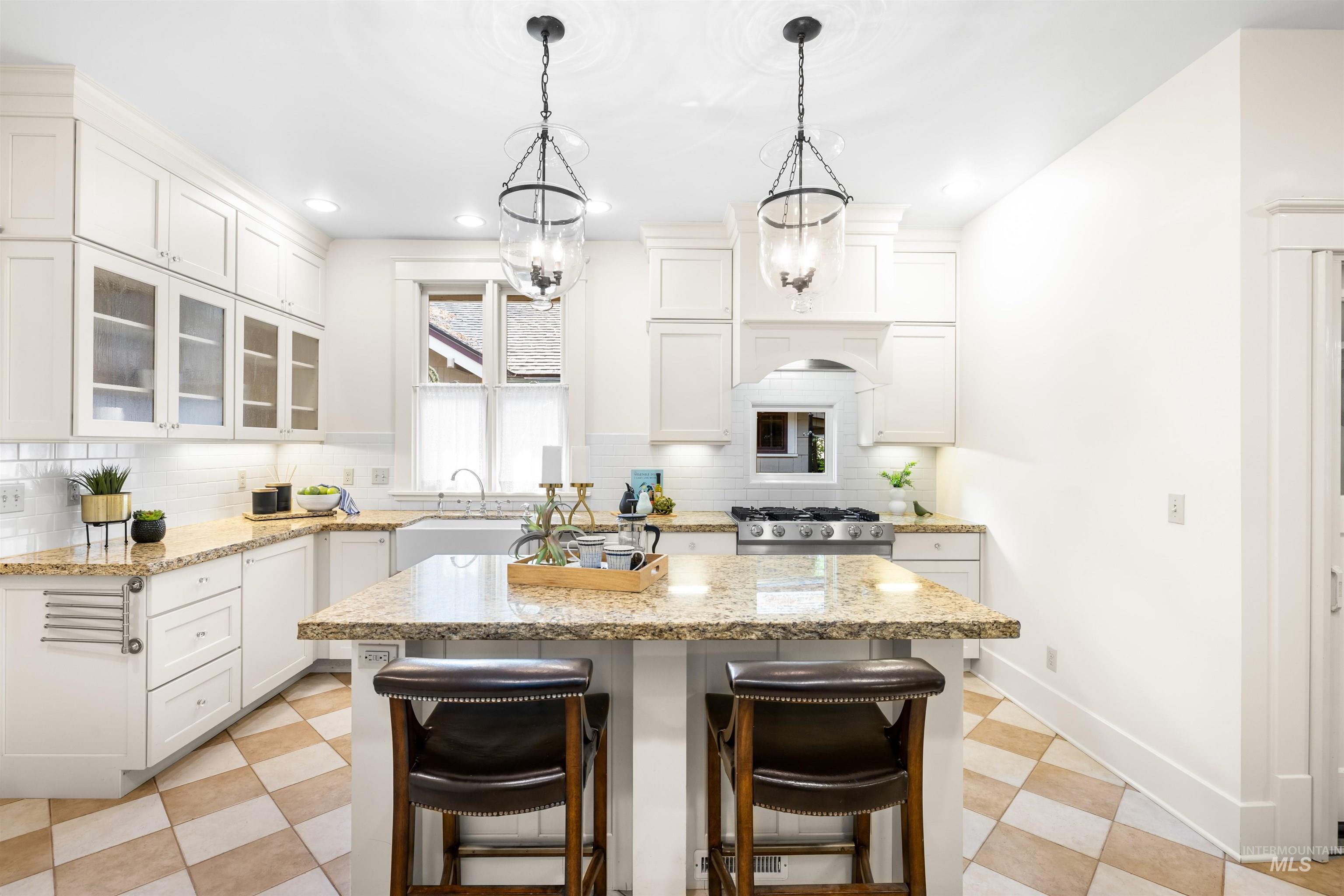 Kitchen featuring white cabinets, a center island, glass insert cabinets, backsplash, and recessed lighting
