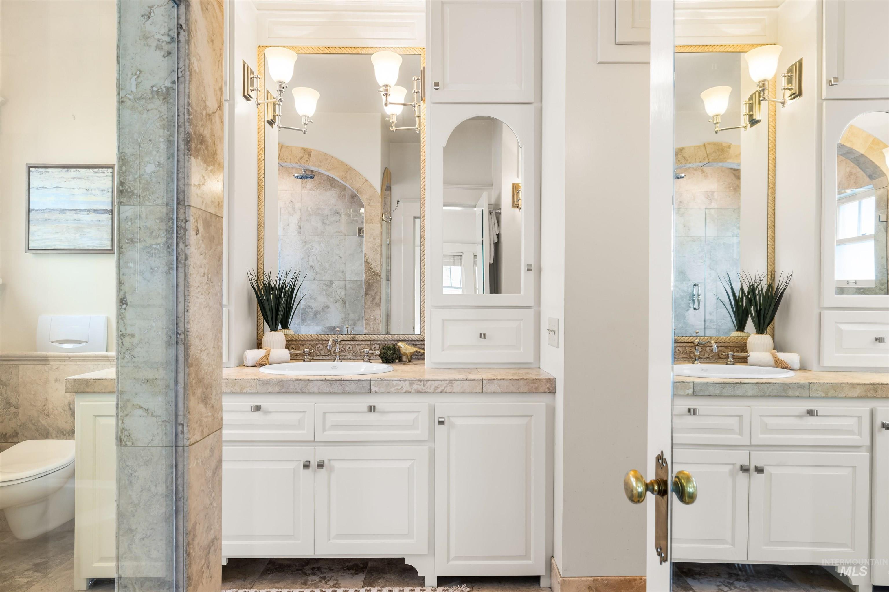 Full bath with two vanities, a shower stall, and tile walls
