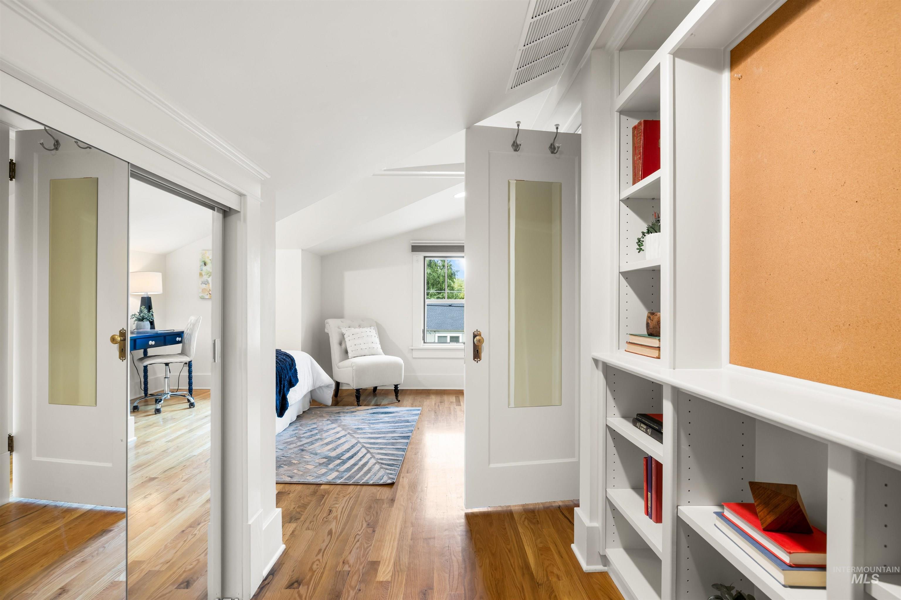 Corridor featuring light wood-style floors, vaulted ceiling, and a desk