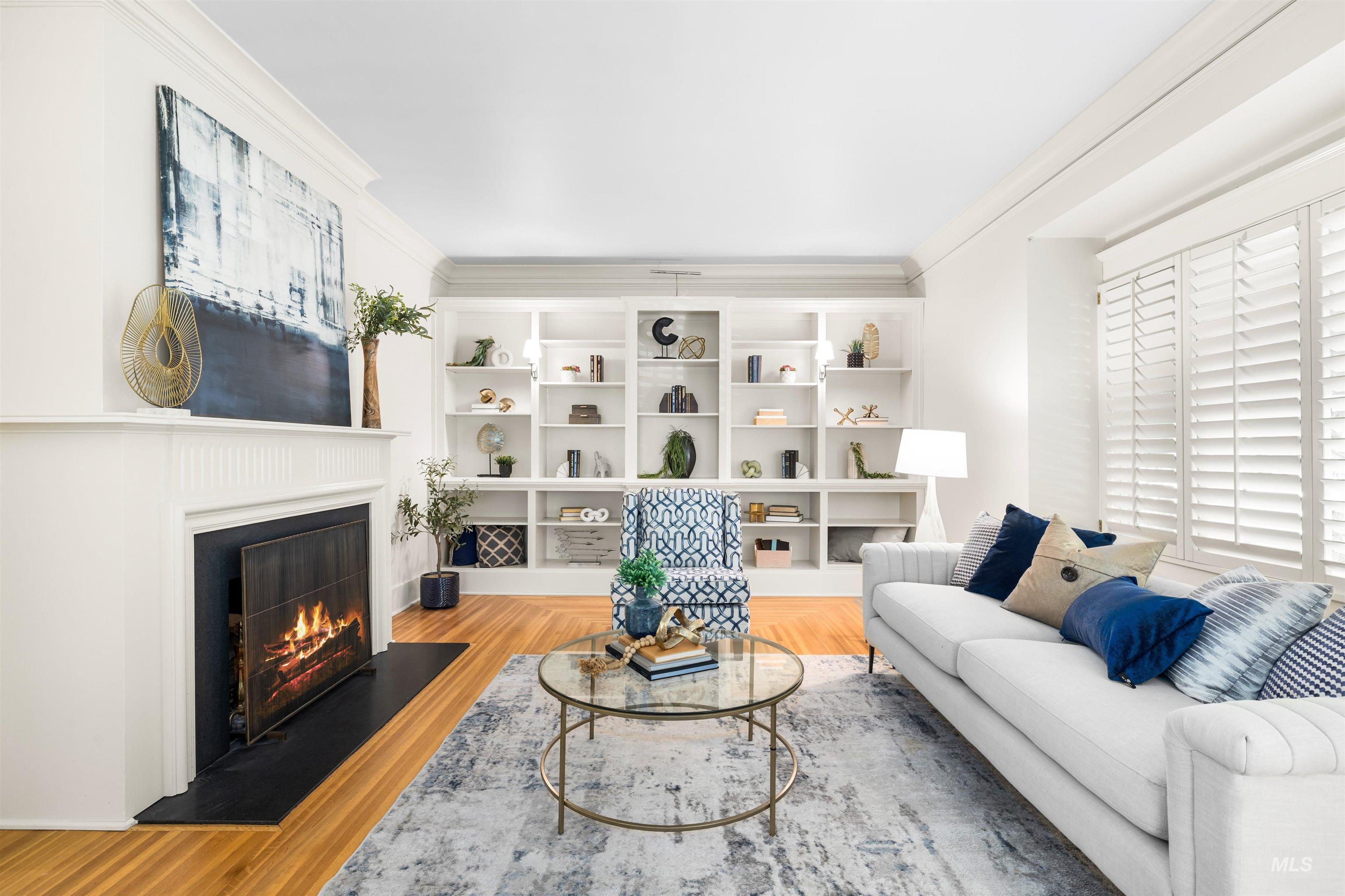 Living room featuring a warm lit fireplace, ornamental molding, and light wood-type flooring