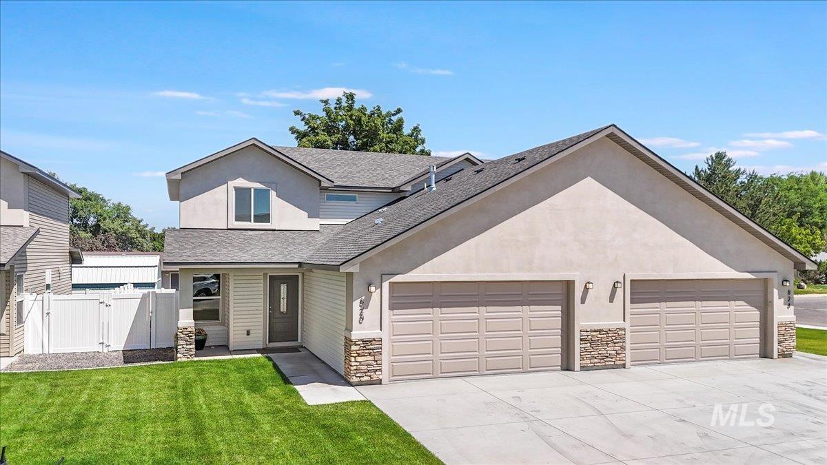 Traditional-style home featuring a gate, roof with shingles, stone siding, a garage, and driveway
