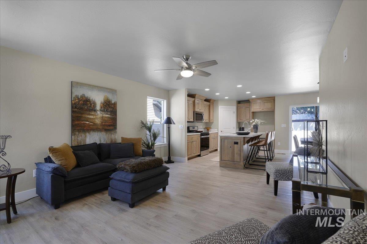 Living room with healthy amount of natural light, light wood-type flooring, a ceiling fan, and recessed lighting