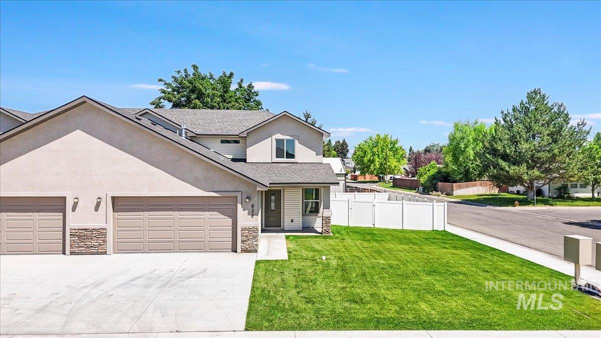 Traditional-style home with stone siding, driveway, an attached garage, and stucco siding