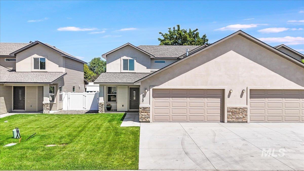 Traditional-style house with stone siding, a gate, driveway, a shingled roof, and an attached garage