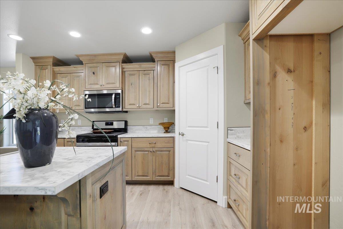 Kitchen with light countertops, stainless steel appliances, light wood-type flooring, recessed lighting, and light brown cabinetry