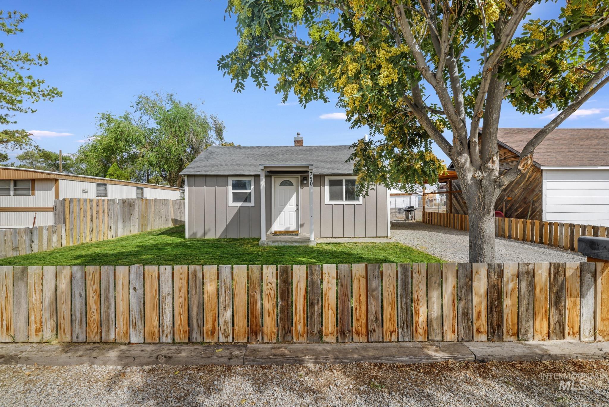 Bungalow with board and batten siding, a chimney, a fenced front yard, and roof with shingles