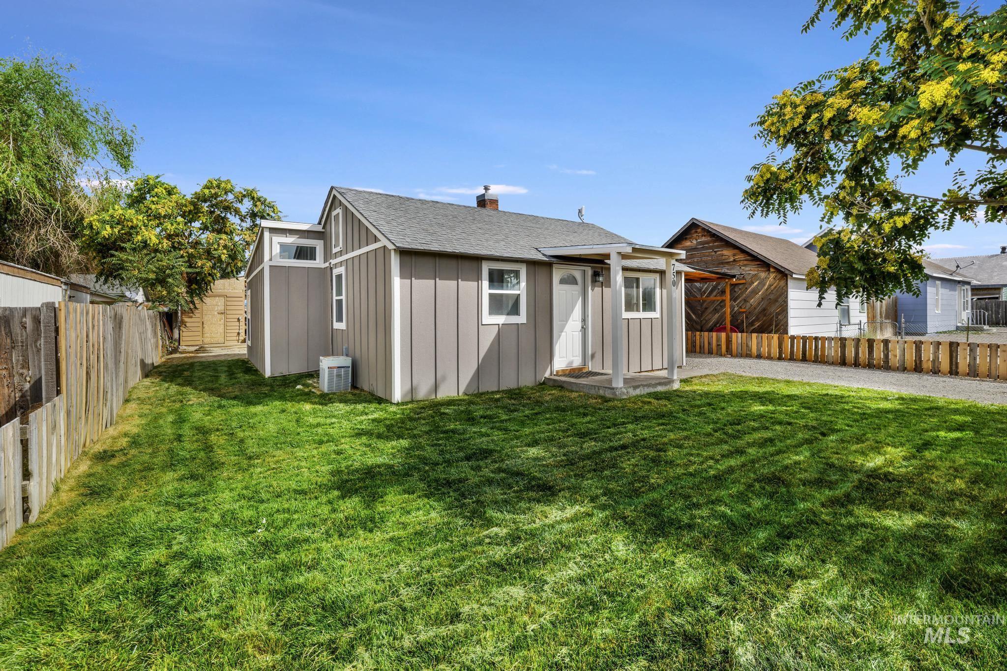 View of front of house featuring board and batten siding, a fenced backyard, a chimney, and roof with shingles