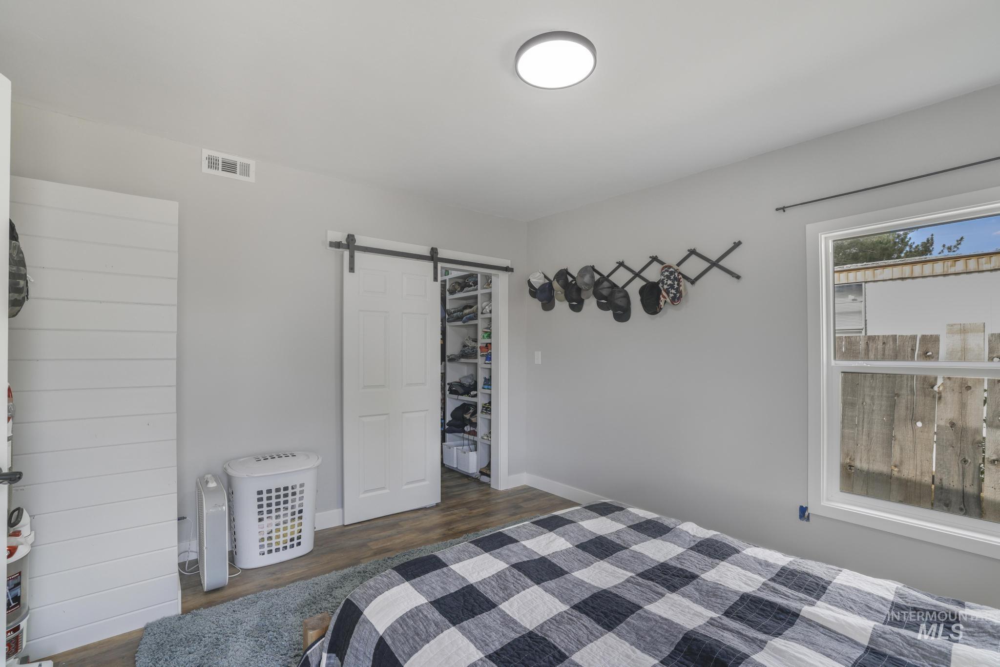 Bedroom featuring a walk in closet, a barn door, and dark wood-style flooring