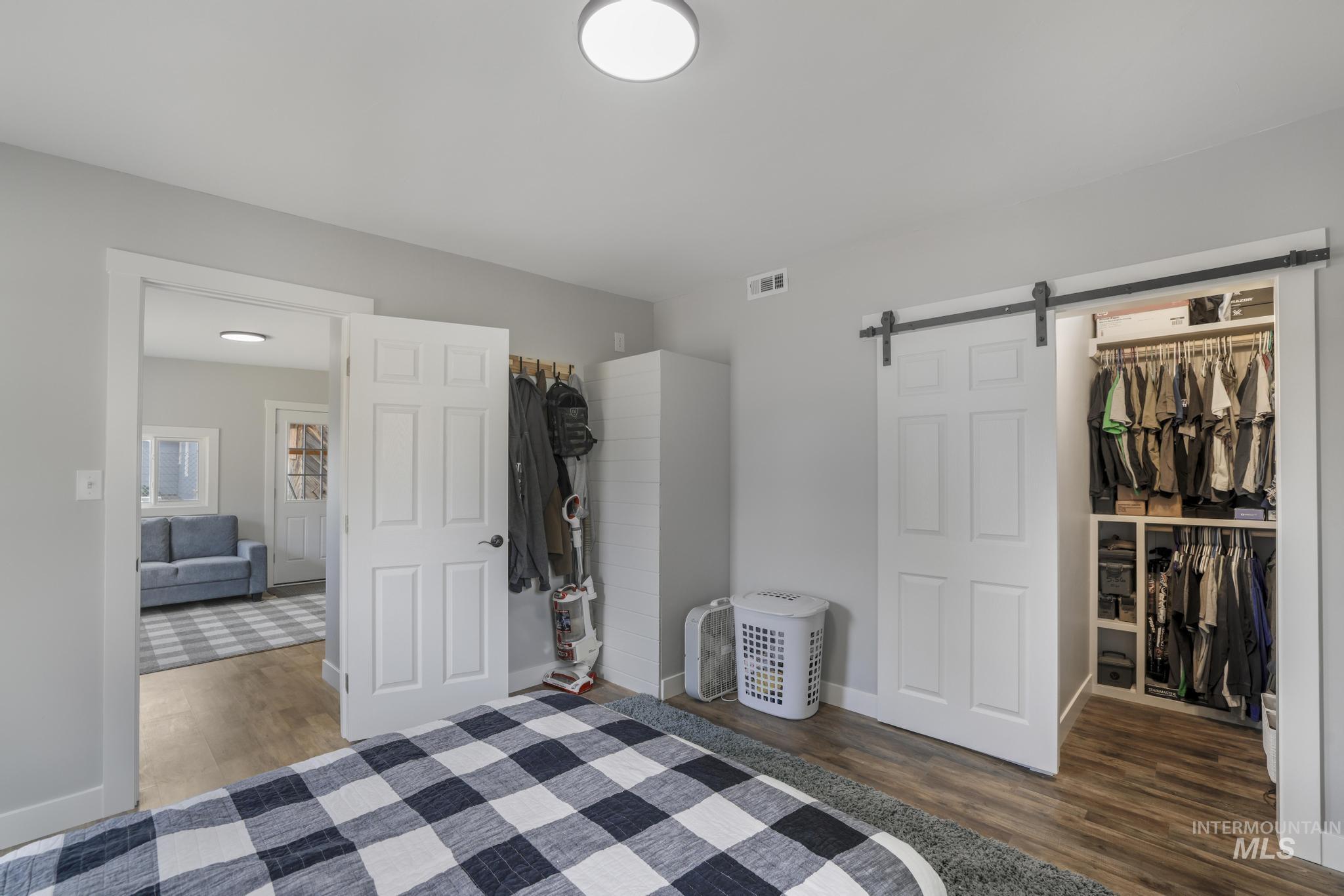 Unfurnished bedroom featuring dark wood-style floors, a walk in closet, and a barn door