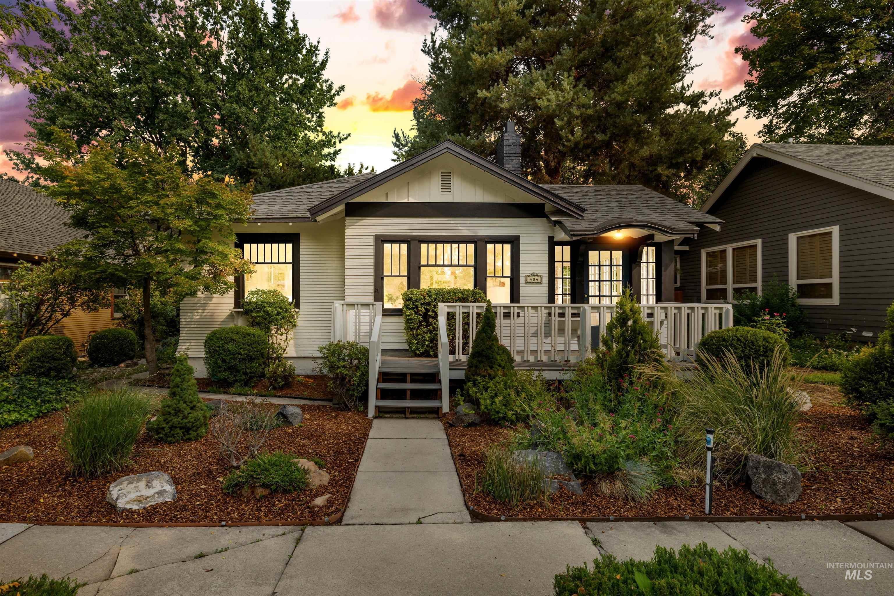 Bungalow-style home with a shingled roof, a chimney, and covered porch