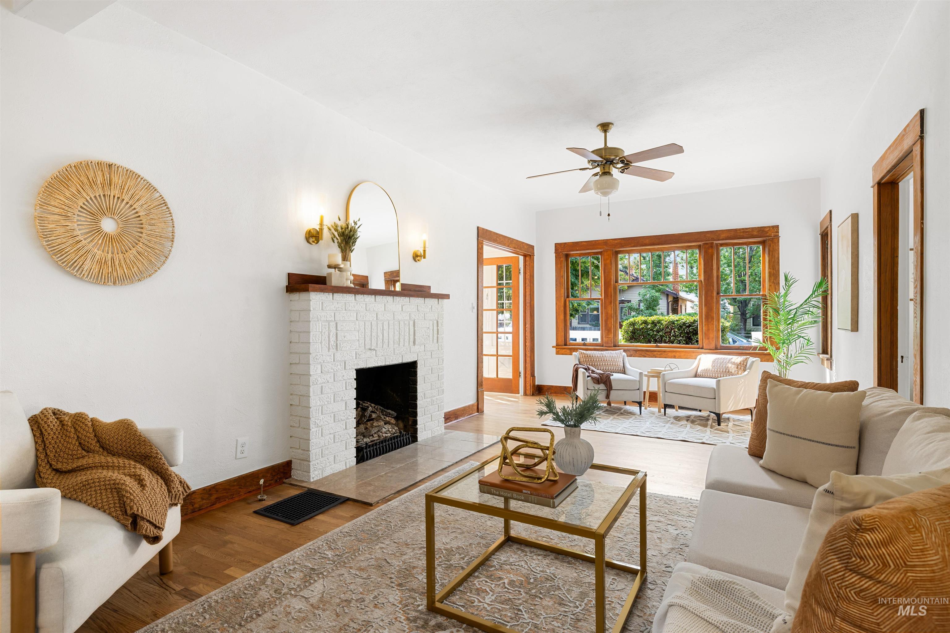 Living room featuring wood finished floors, a brick fireplace, and ceiling fan