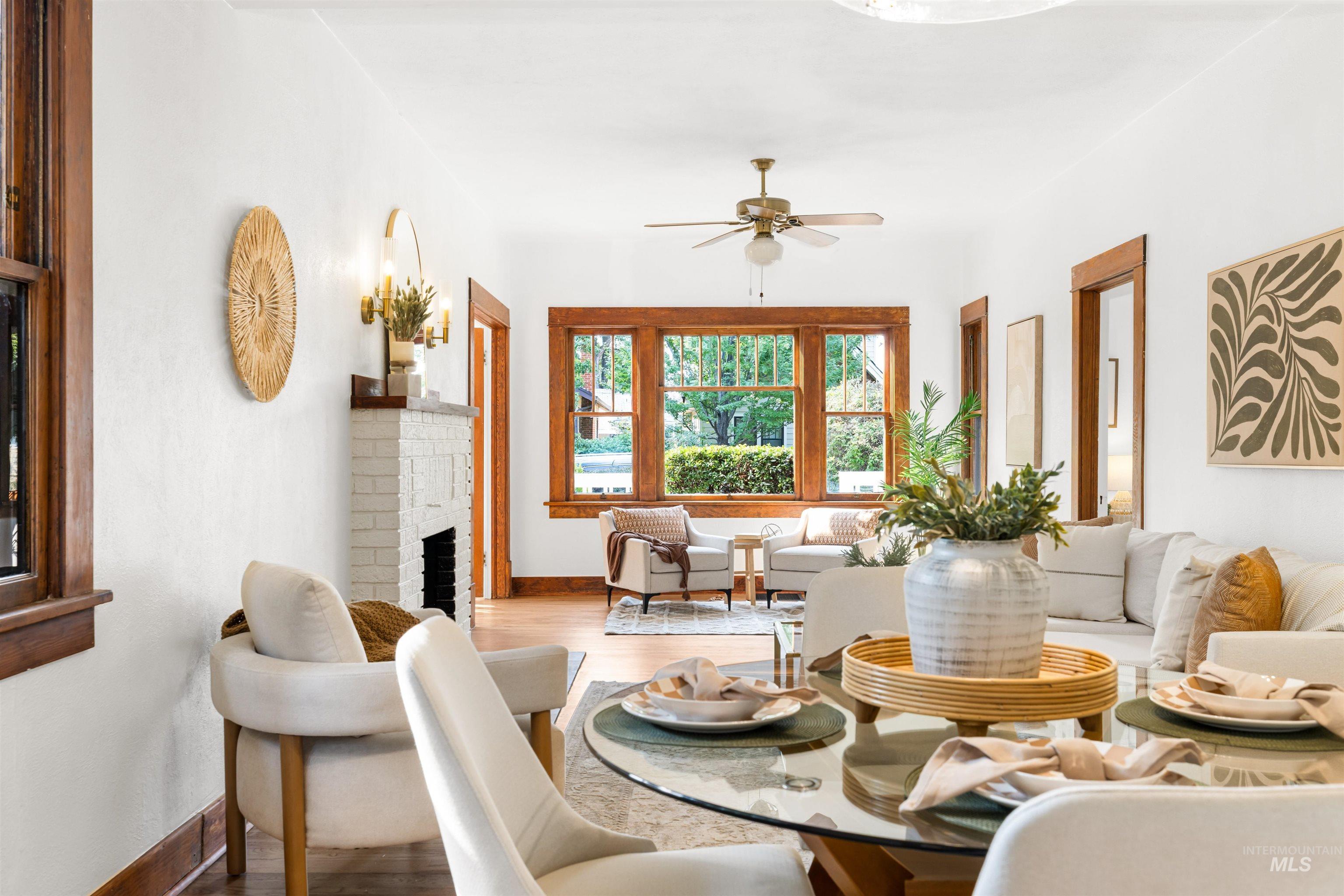 Living area featuring wood finished floors, a brick fireplace, and ceiling fan