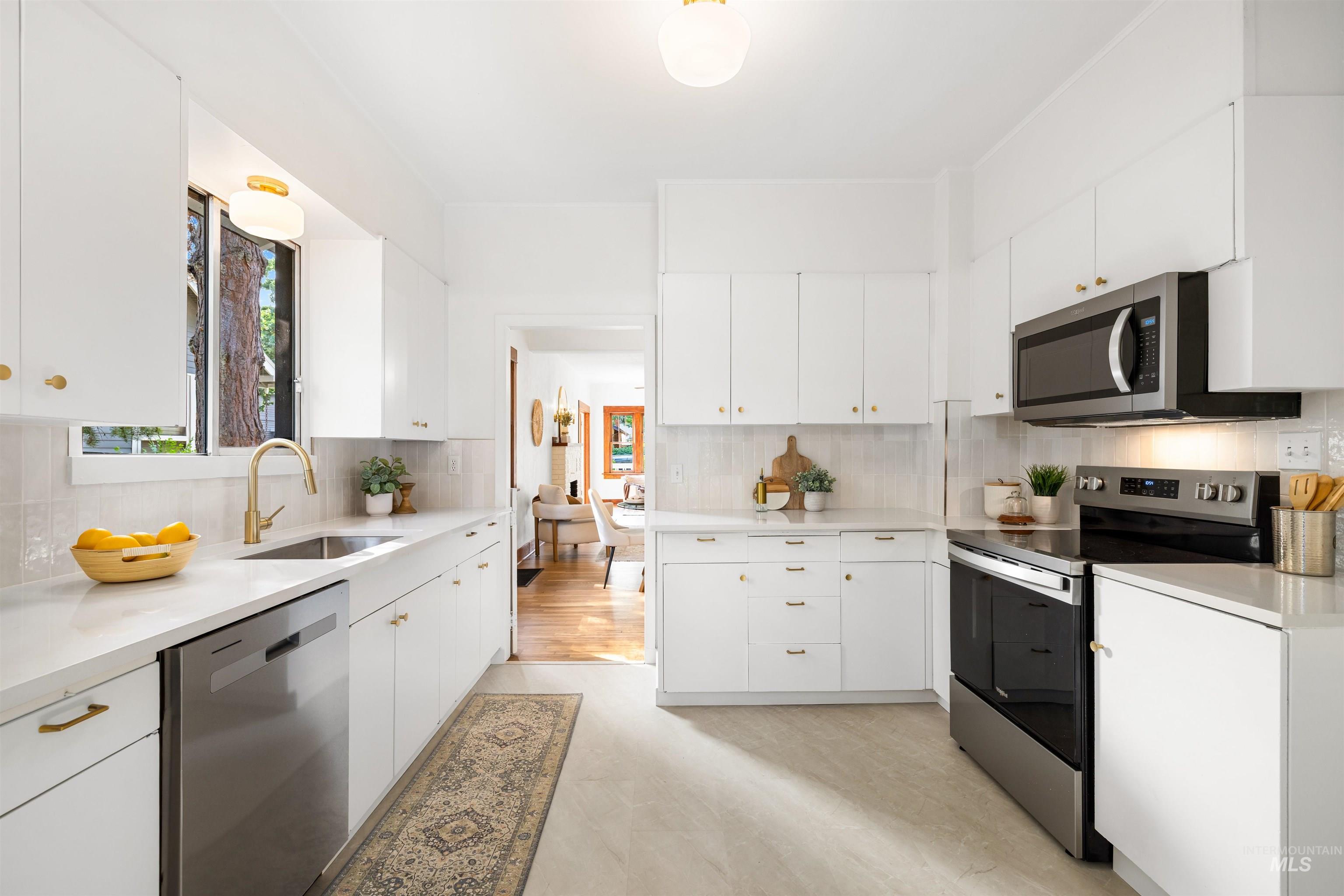 Kitchen featuring appliances with stainless steel finishes, backsplash, white cabinets, light stone countertops, and modern cabinets