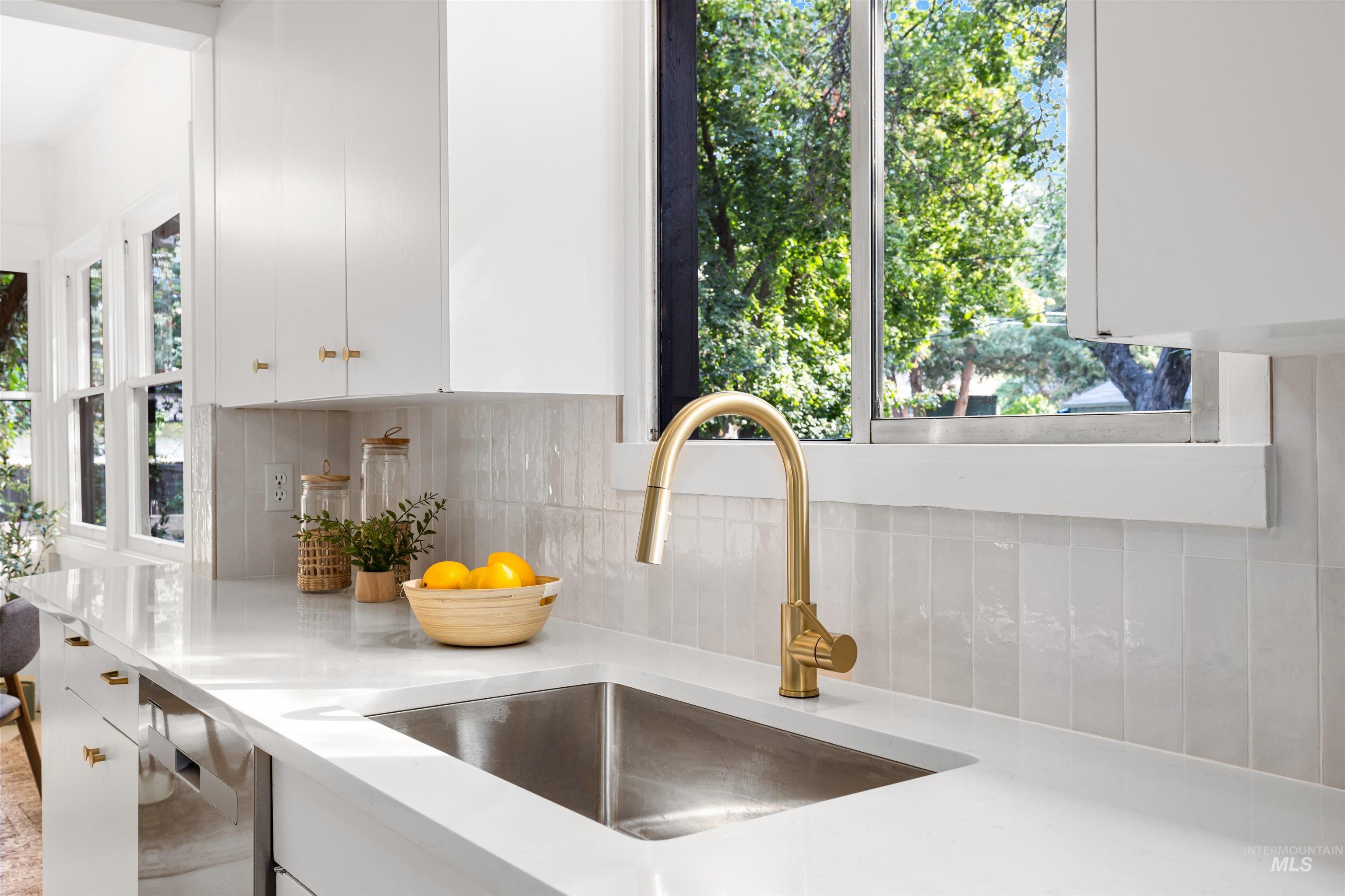Kitchen view of white cabinetry, backsplash, and dishwasher