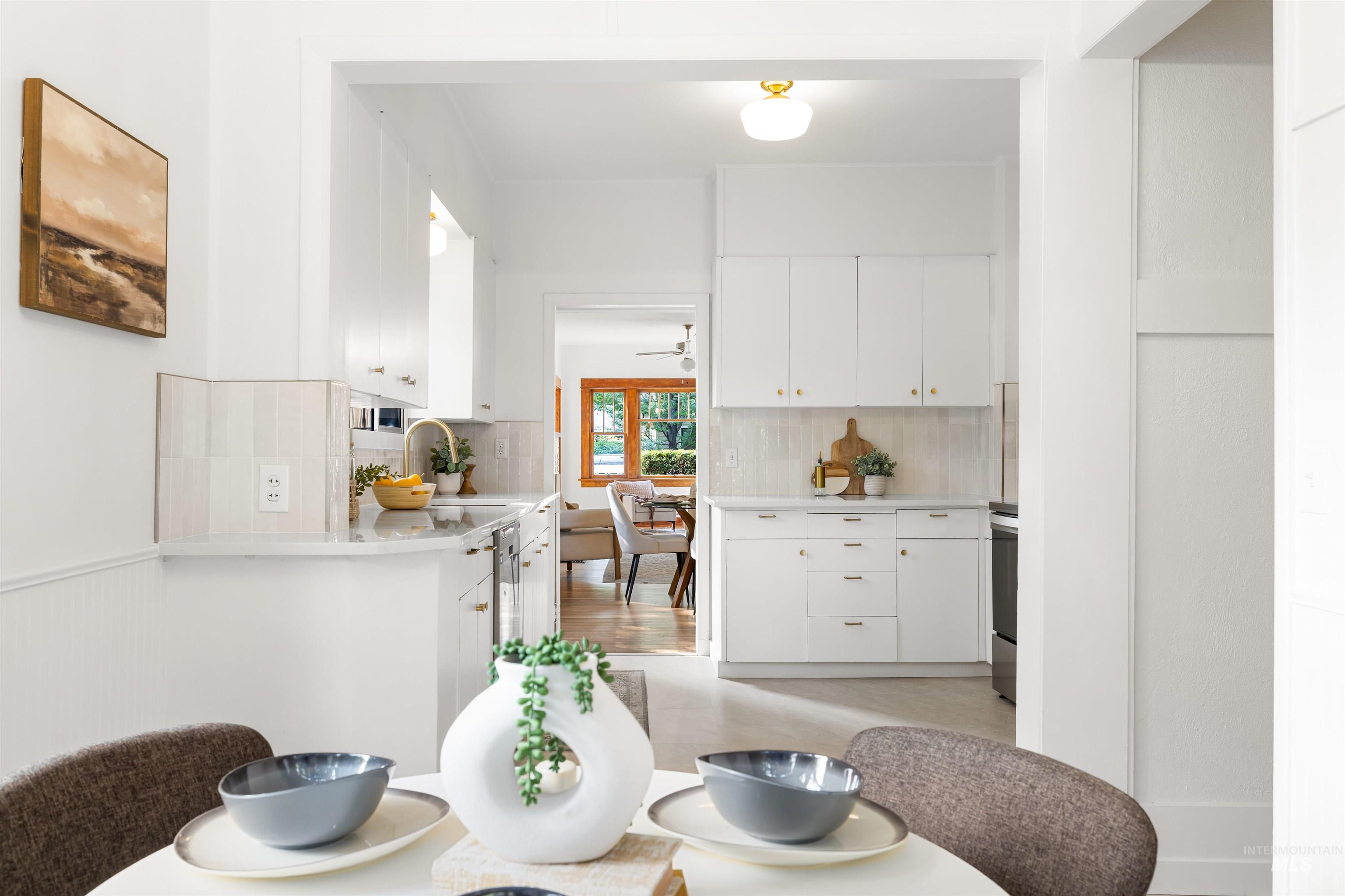 Kitchen with decorative backsplash, white cabinetry, ceiling fan, light stone counters, and stainless steel range oven