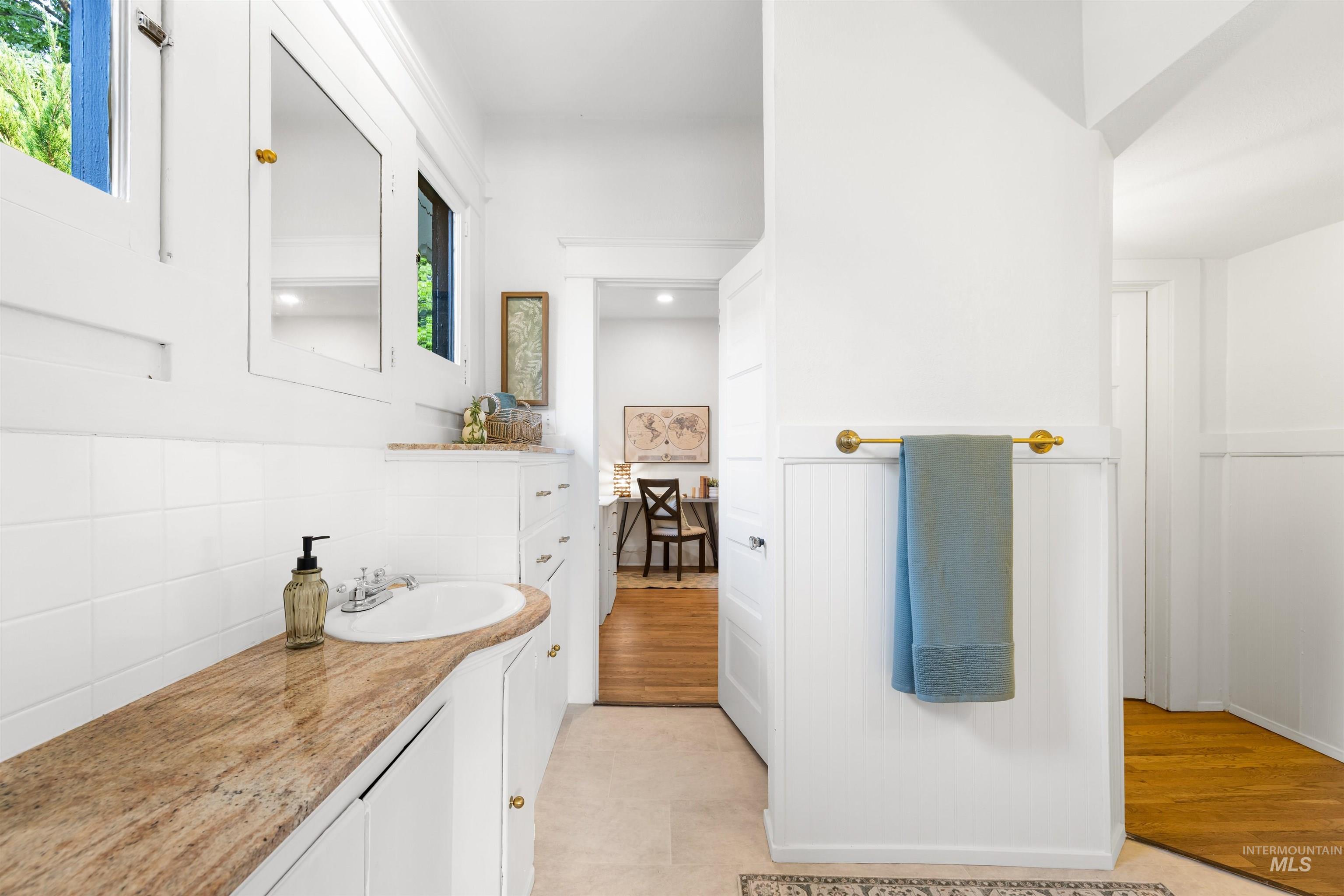 Bathroom with vanity, light wood-style flooring, and tasteful backsplash