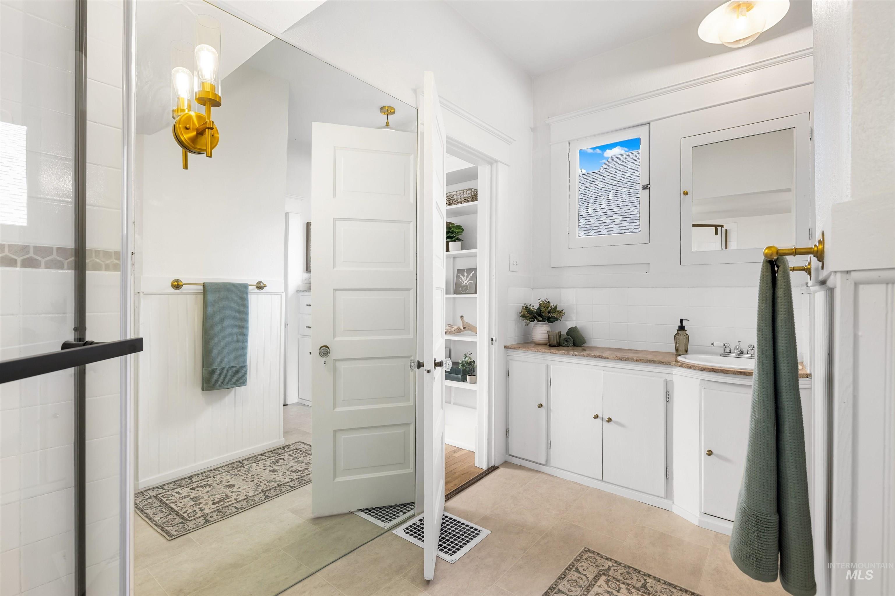 Bathroom featuring vanity, tasteful backsplash, and light tile patterned floors